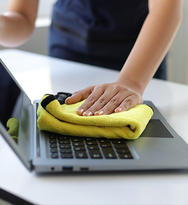 Young Asian cleaning woman uses a towel to clean a computer using cleaning solution in her home office