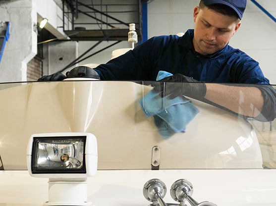 Young handsome professional guy (male) cleaner, washes the yacht after polishing and lining ceramics on the yacht