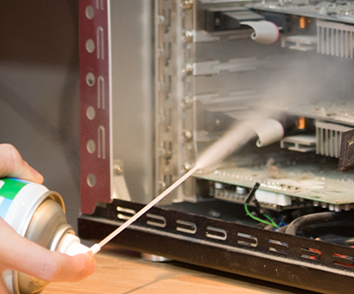 using a can of compressed air to clean the inside of a PC